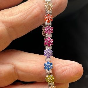 Tennis bracelet with three diamond chips between each flowered colored diamond.